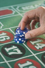 Man placing gambling chips on roulette table.