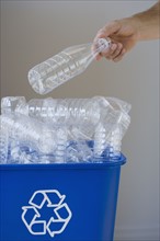 Man putting bottle in recycling bin.