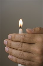 Man holding hand in front of candle.