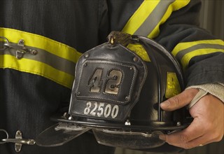 Close up of firefighter holding helmet.