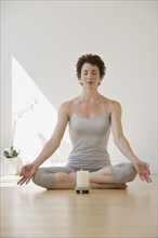 Woman meditating next to candle.