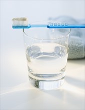 Toothbrush with toothpaste on glass of water.