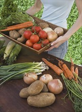 Woman holding basket of fresh vegetables.
