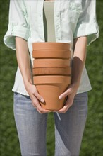 Woman holding stack of terracotta pots.
