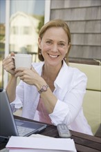 Woman with coffee mug next to laptop.