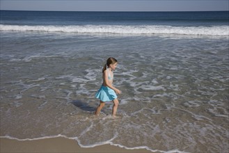 Girl walking in ocean surf.