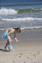 Girl collecting shells at beach.