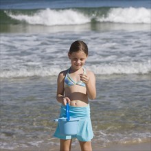 Girl looking at shell at beach.
