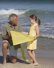 Father and daughter with kite at beach.