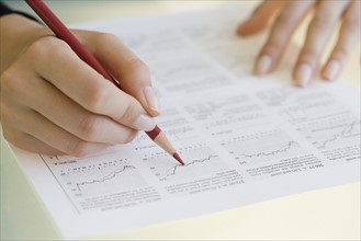 Woman writing on financial charts.
