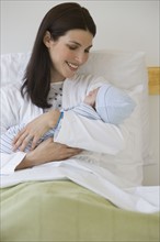 Mother holding newborn in hospital.