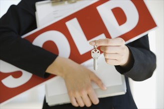 Real Estate agent holding clipboard and Sold sign.