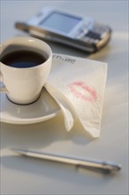 Lipstick on napkin next to coffee.