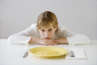 Teenaged girl looking at empty plate.
