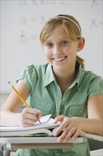 Teenaged girl writing at school desk.