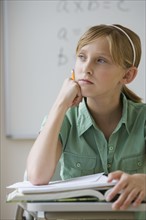 Teenaged girl thinking at school desk.