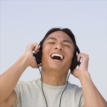 Asian man listening to headphones.