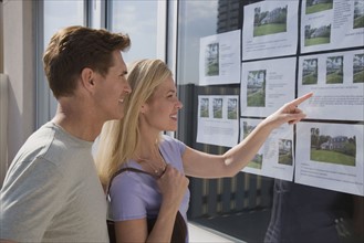 Couple looking at real estate window.