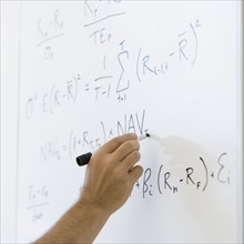 Man writing formulae on whiteboard.