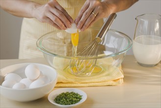 Chef cracking egg into bowl.