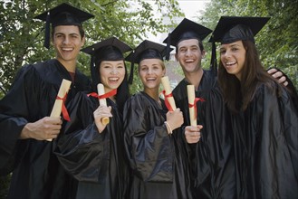 Group of college graduates holding diplomas.