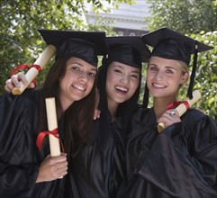 Female college graduates holding diplomas.
