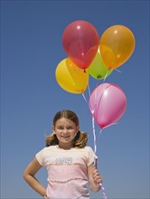 Girl holding balloons.