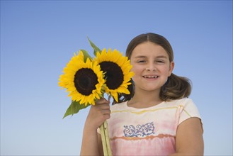 Girl holding sunflowers.