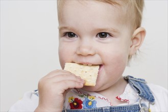 Female toddler eating a cracker. Date : 2006
