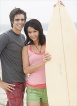 Couple holding surfboard and smiling. Date : 2006