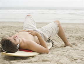 Man laying on surfboard at beach. Date : 2006