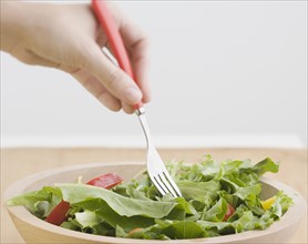 Woman sticking fork in salad. Date : 2006