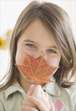 Girl holding autumn leaf in front of face. Date : 2006