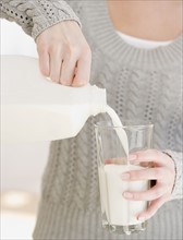Woman pouring glass of milk. Date : 2007