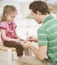 Father putting bandage on daughter. Date : 2007