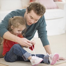 Father teaching daughter how to tie shoe. Date : 2007
