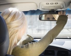 Woman adjusting car rear view mirror. Date : 2007