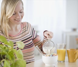 Woman pouring milk into cereal. Date : 2007