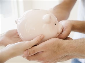 Three people holding piggy bank. Date : 2007