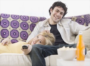 Couple watching television on sofa. Date : 2007