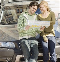Couple on front of car looking at map. Date : 2007