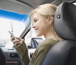 Woman looking at cell phone in car. Date : 2007