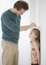 Father measuring daughter’s height on wall. Date : 2007