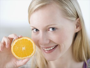 Woman holding half of orange. Date : 2007
