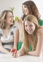 Teenage girls laughing and holding apples. Date : 2007