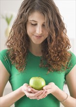 Teenage girl holding apple and looking down. Date : 2007