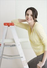 Woman on ladder with roll of wallpaper. Date : 2007