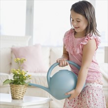 Girl watering plant indoors. Date : 2006