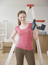 Woman holding cordless drill in new house. Date : 2006