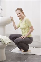 Woman crouching on bathroom scale. Date : 2006